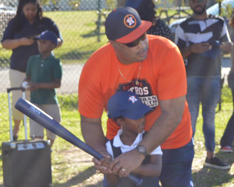 Photo of an adult helping a child play baseball